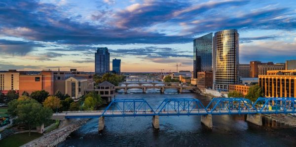 City skyline with multiple bridges over a river at sunset.