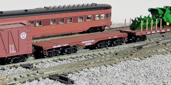 Model train cars on detailed tracks with gravel and equipment.