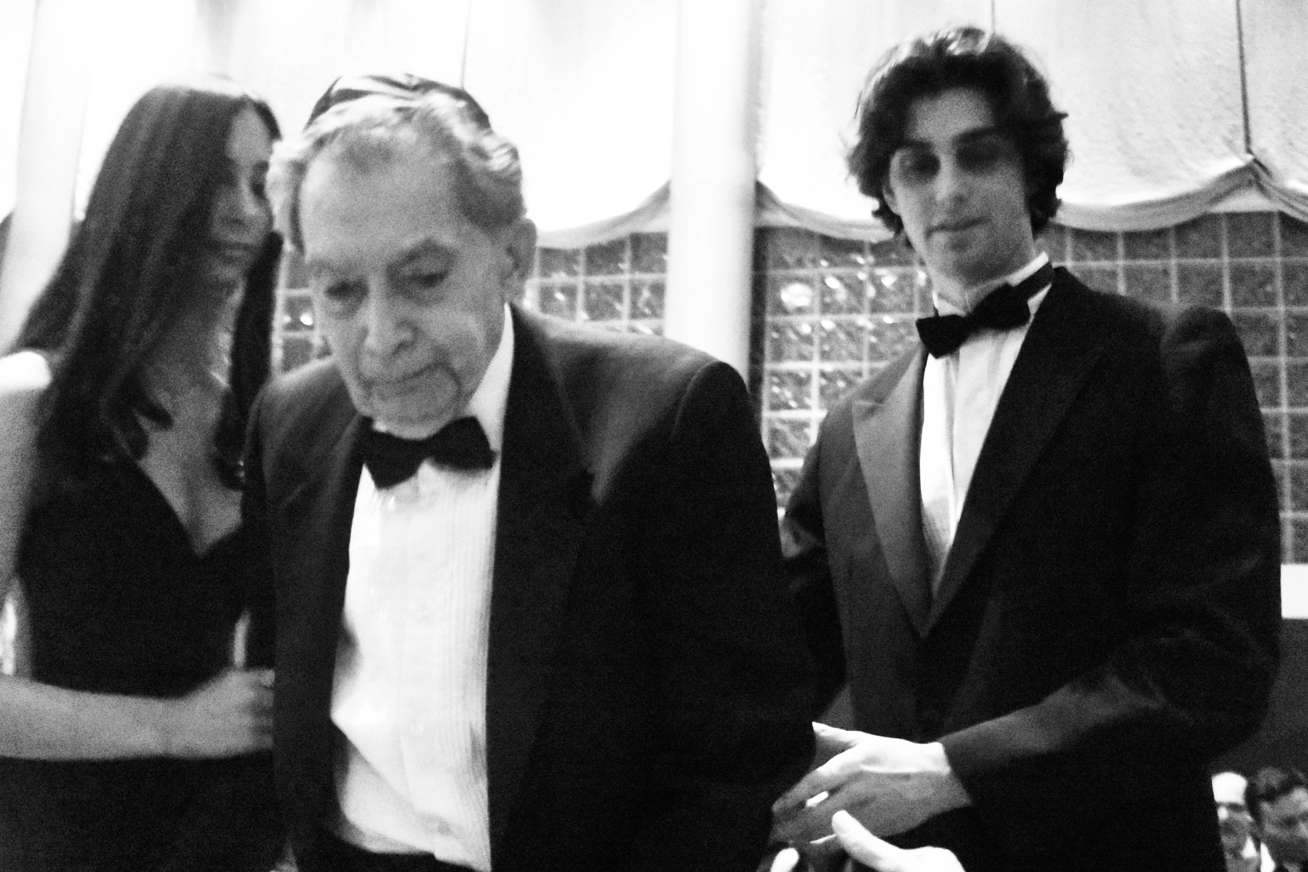 Three people dressed formally, with an older man in the center.