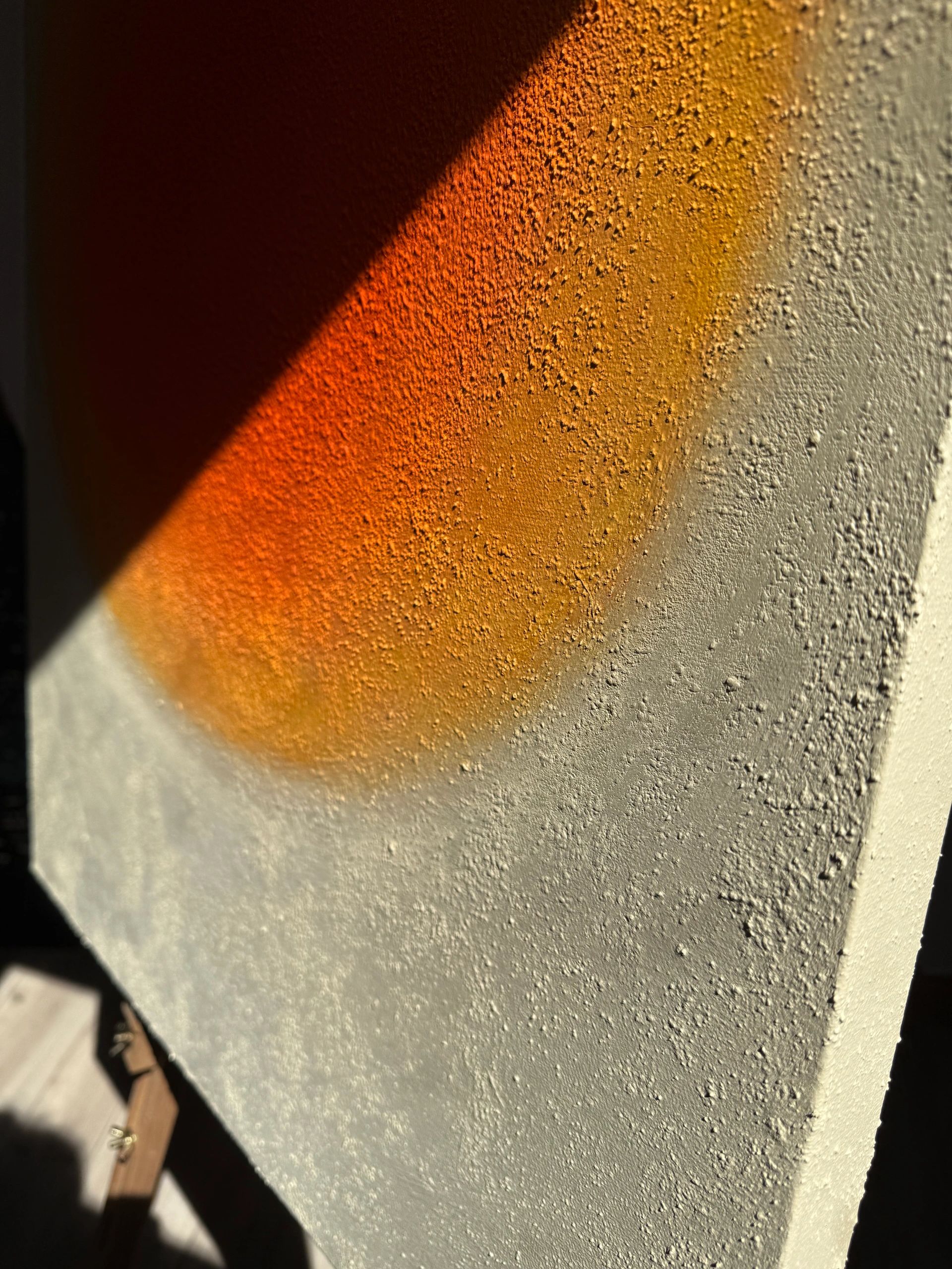 Sunlight casting an orange shadow on a textured wall corner.