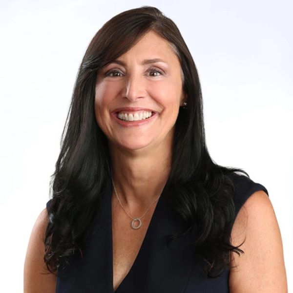 Smiling woman with long dark hair and a necklace.