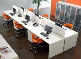 Modern office workspace with orange chairs and desktop computers.