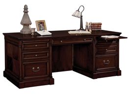 Elegant wooden desk with drawers, lamp, books, and decor items.