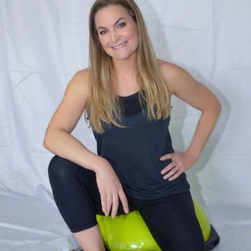 Woman in workout attire sitting on a green exercise ball.