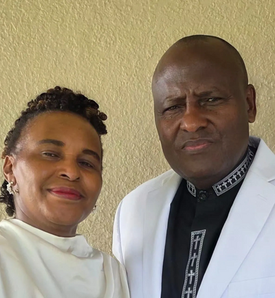 A smiling woman and a serious man posing together indoors.