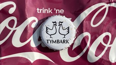 Weiße Tymbark-Flaschenkappe auf rotem Coca-Cola-Hintergrund.