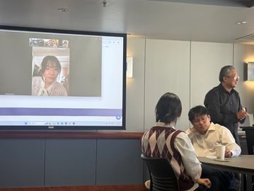 People in a meeting room with video call projected on screen.