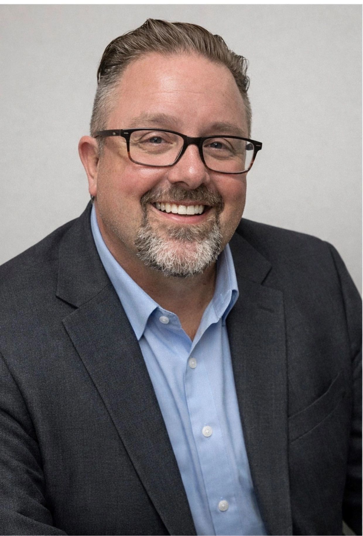 Smiling man in glasses and suit jacket.