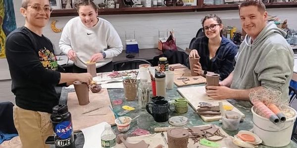 Four people crafting pottery together in an art studio.