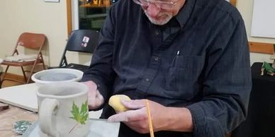 Man painting a small wooden object indoors.