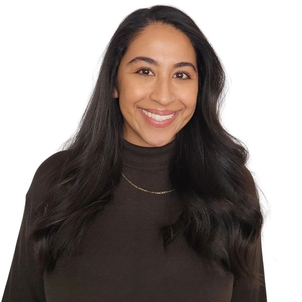 Smiling woman with long dark hair wearing a brown turtleneck sweater.