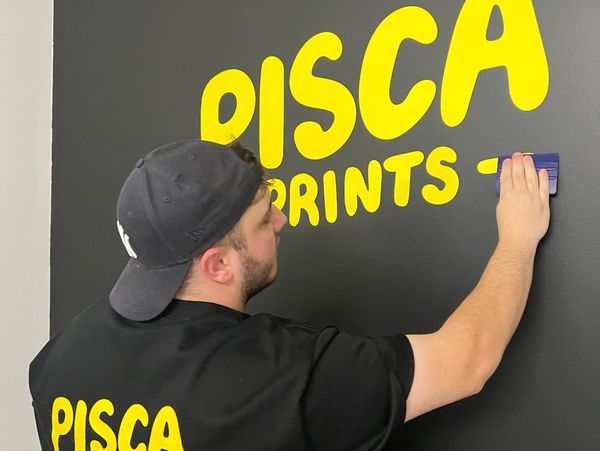 Pisca Prints applying wall decal to factory.