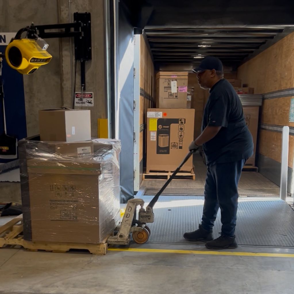 Worker moving pallets in a warehouse truck.
