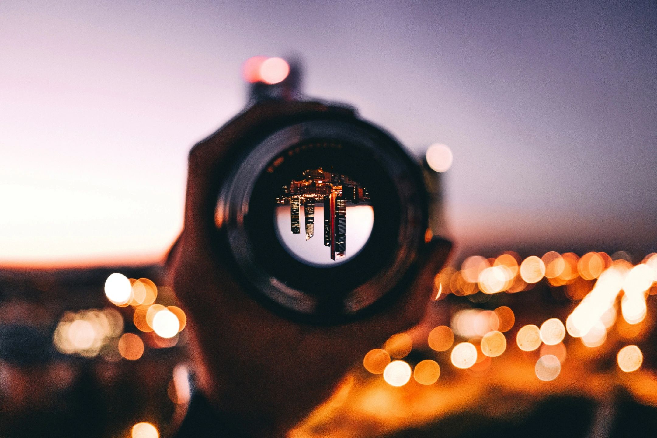 City skyline seen upside down through a camera lens at dusk.