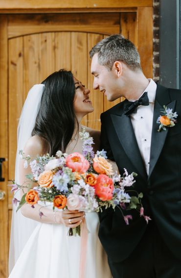 Couple looking at each other lovingly with bride holding a pastel spring bouquet at the City Winery 