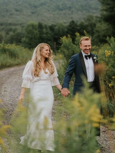 Couple walking though a field of wildflowers at Hayfield Catskills wedding