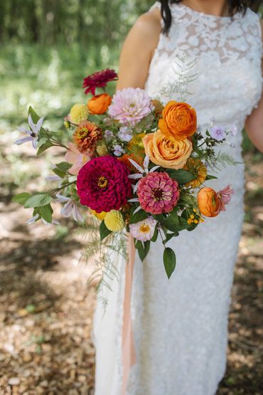 Bride holding a colorful summer bouquet with pink, orange and yellow flowers