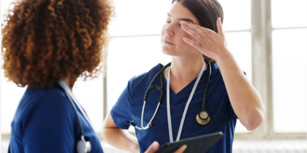 2 nurses, 1 is stressed with hand to head