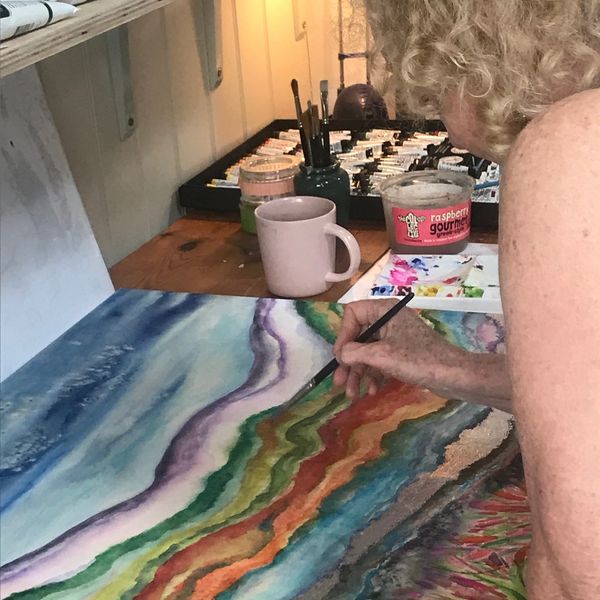 Person painting a colorful landscape on a canvas.