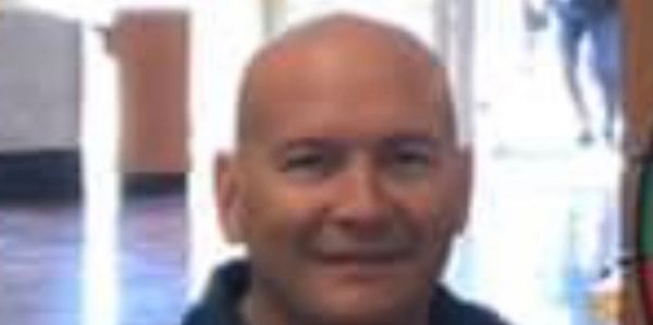 Smiling bald man indoors with blurred background.