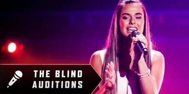Young woman singing during The Blind Auditions with a microphone.
