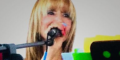 Woman singing into a microphone with colorful music stand.