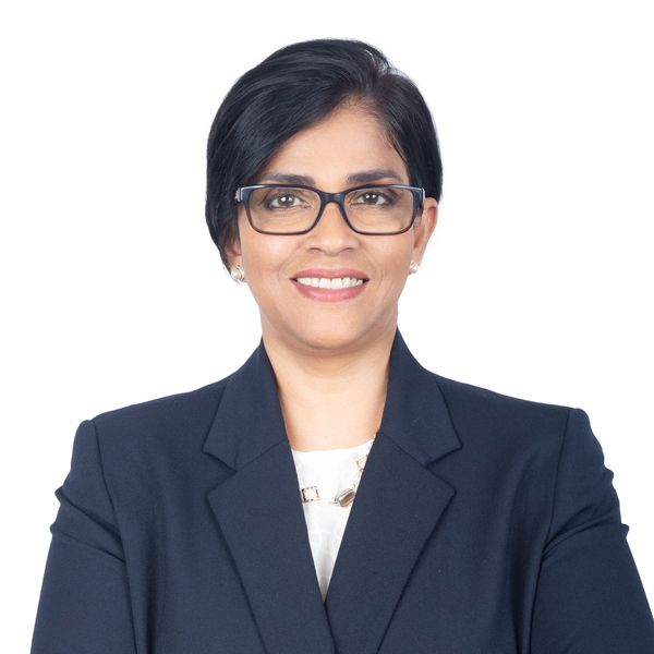 Confident woman in glasses and dark blazer smiling at the camera.