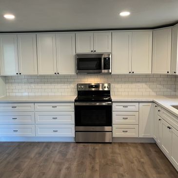 Remodeled kitchen. White cabinets and subway tiles, stainless steel appliances. Wood floor.