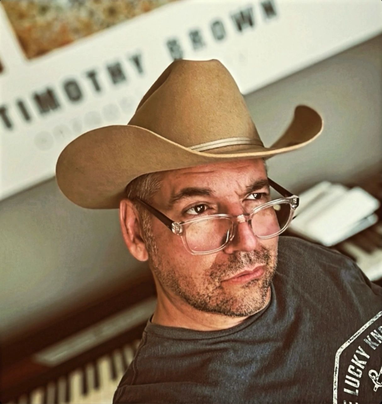 Man wearing a tan cowboy hat and glasses.