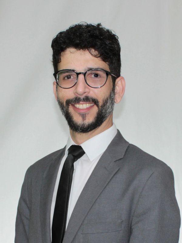Homem sorridente de terno cinza e gravata preta.