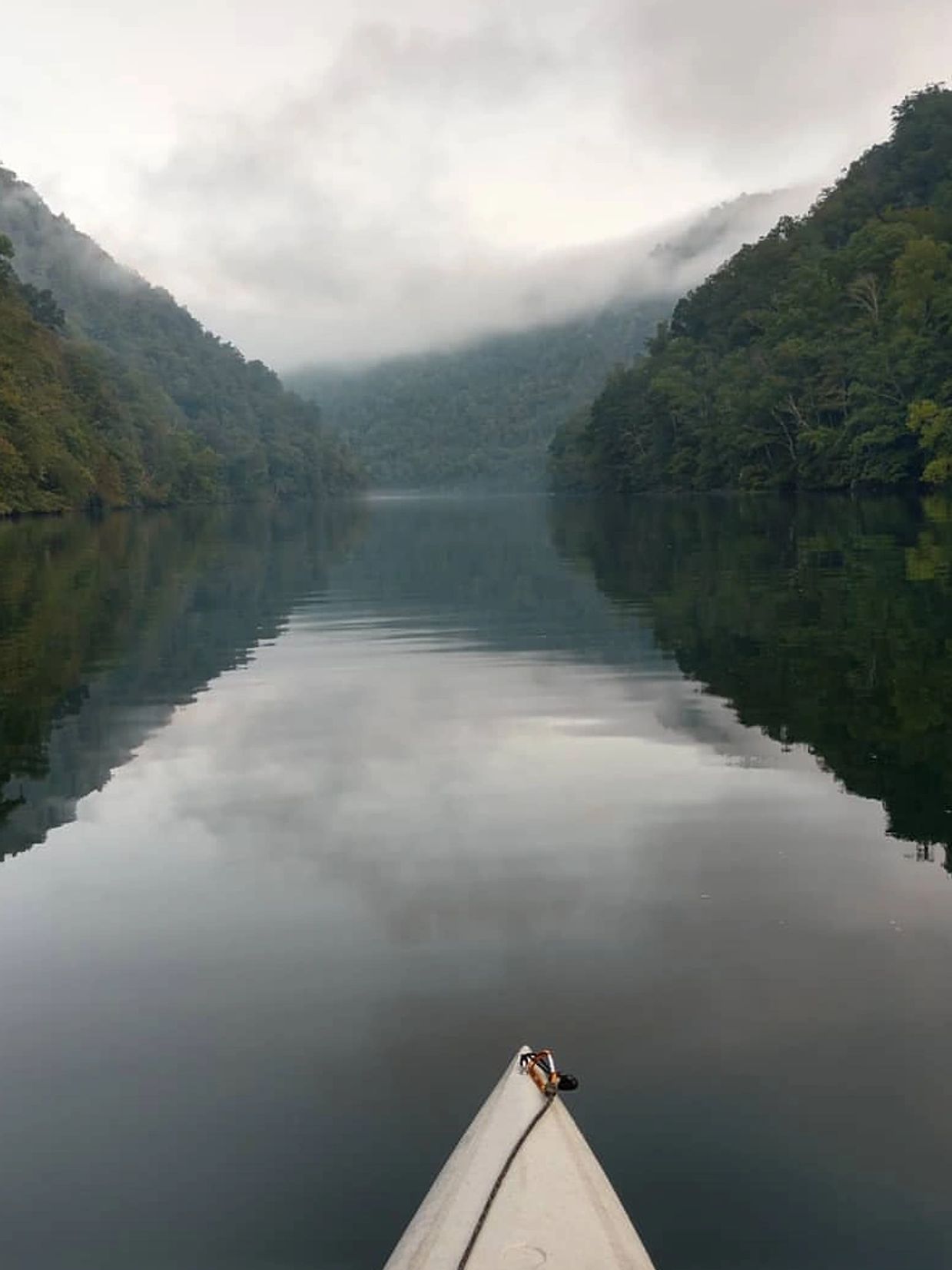 Kayak on smooth water with mountains in background and reflection. 