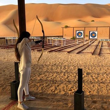 Person practicing archery in a desert range.