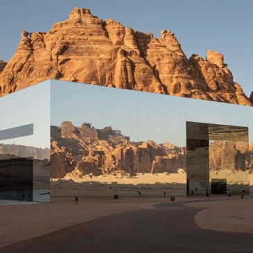 Modern mirrored building in a desert mountain setting.