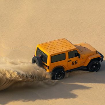 Yellow off-road vehicle driving fast on sand.