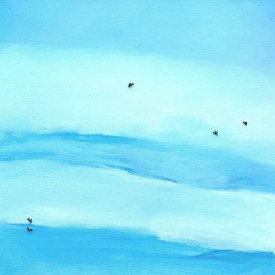 A serene aerial view of swimmers dispersed in a calm, blue sea.