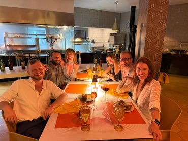 A group of six friends enjoying dinner at a warmly lit restaurant.