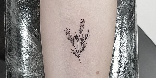 Minimalist black ink tattoo of three thistle flowers on skin.