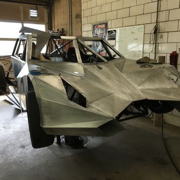 Partially assembled futuristic metal car frame in a workshop.