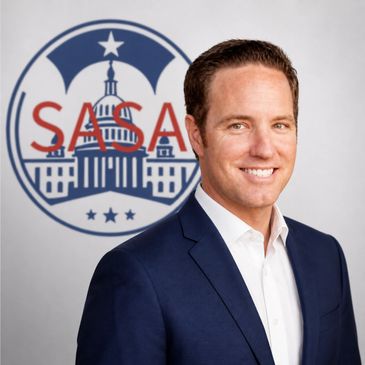 Professional man in a suit posing in front of a SASA logo.