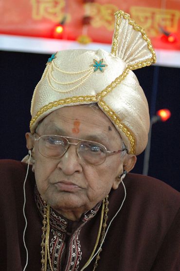 Elderly man in traditional headgear and glasses.