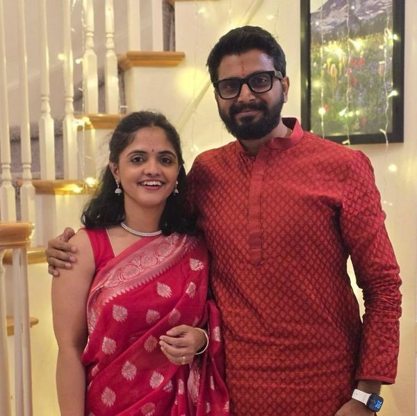 Couple dressed in traditional Indian attire smiling indoors.