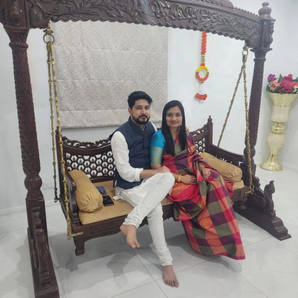 Couple sitting on a wooden swing indoors.
