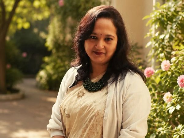 Woman in traditional attire with a necklace outdoors.
