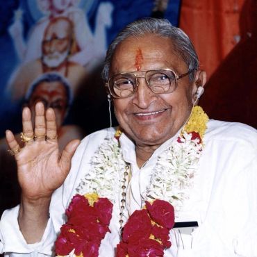 Smiling elderly man with garlands waving.