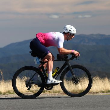 Cyclist riding on a road against a scenic mountain backdrop.