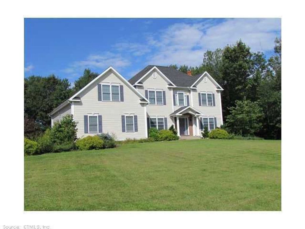 Large white two-story house with a spacious green lawn under a blue sky.