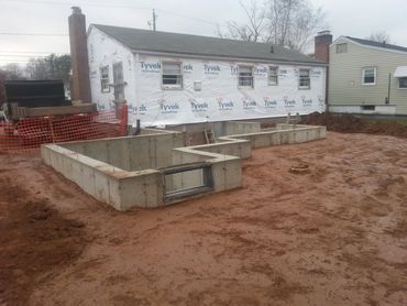 Concrete foundation installed and backfilled. The existing house siding has been removed and new Tyv