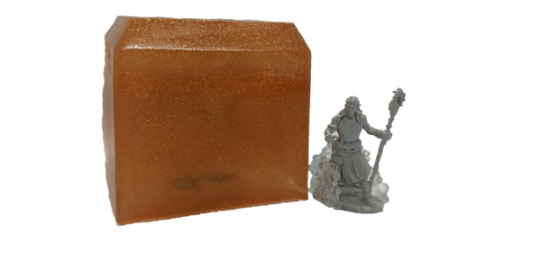 A bronze colored cube of soap with an adventurer mini trapped inside. A adventurer mini is next to t
