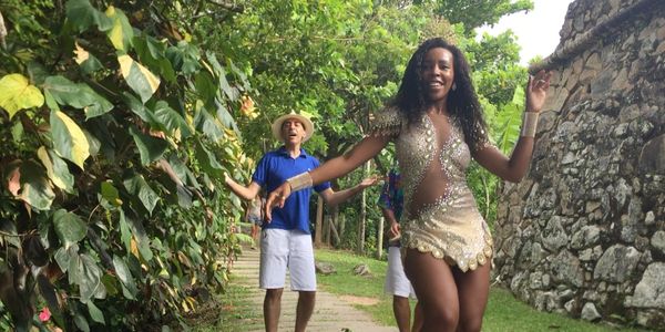 Mário Moita cantando num jardim e uma bailarina mulata dançando.