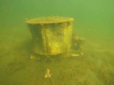 Underwater view of a rusty, submerged metal object on the seabed.